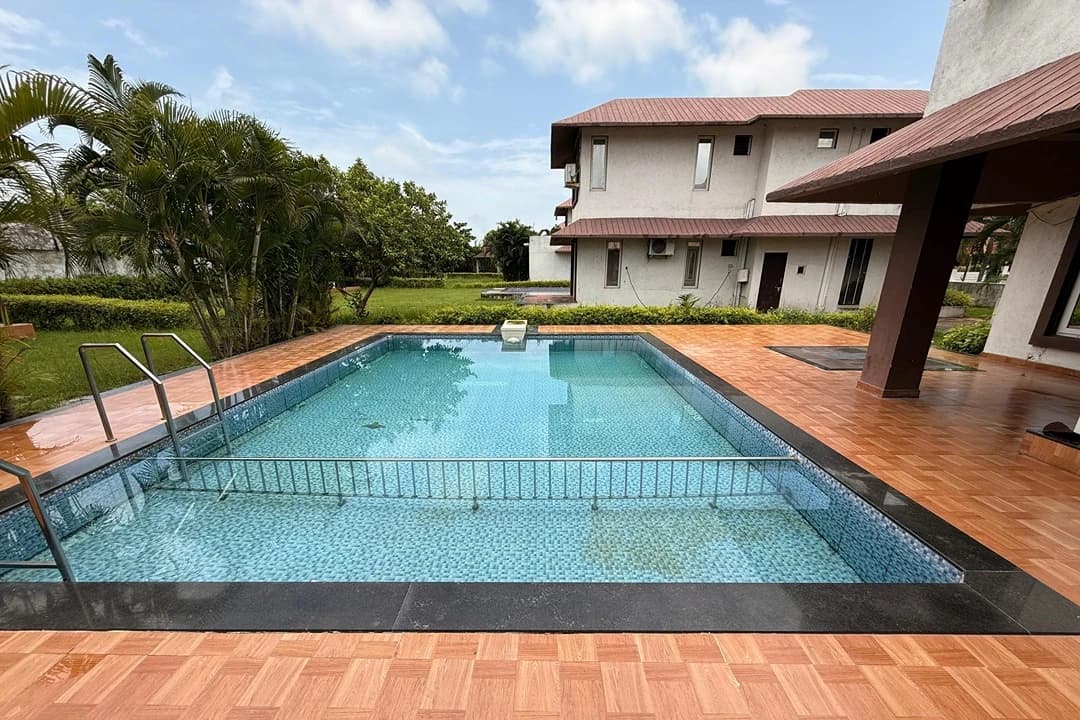 Swimming pool overlooking green fields at a villa in Ubharat, Navsari