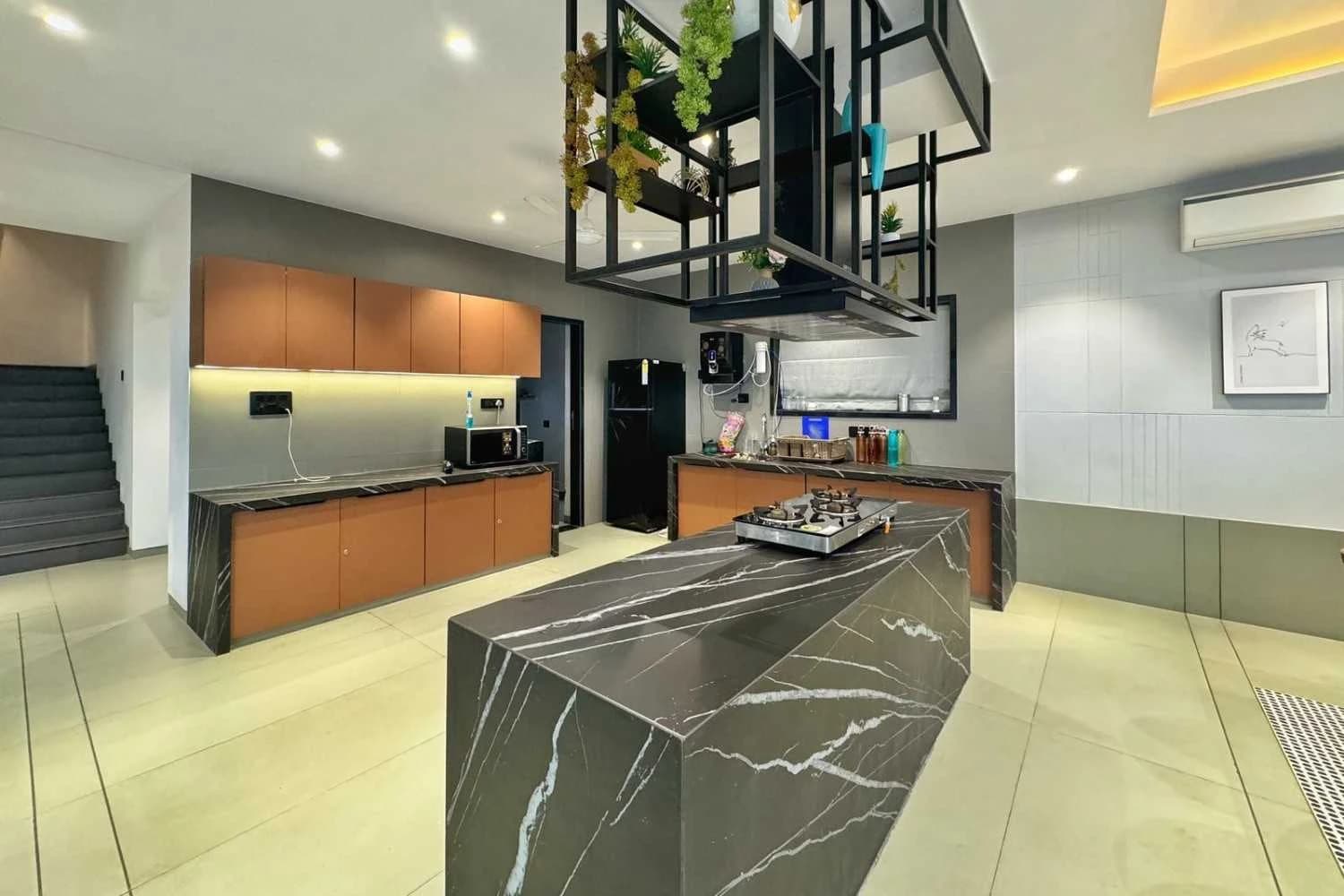 Modern kitchen with a dark marble island at a premium farmhouse near Surat