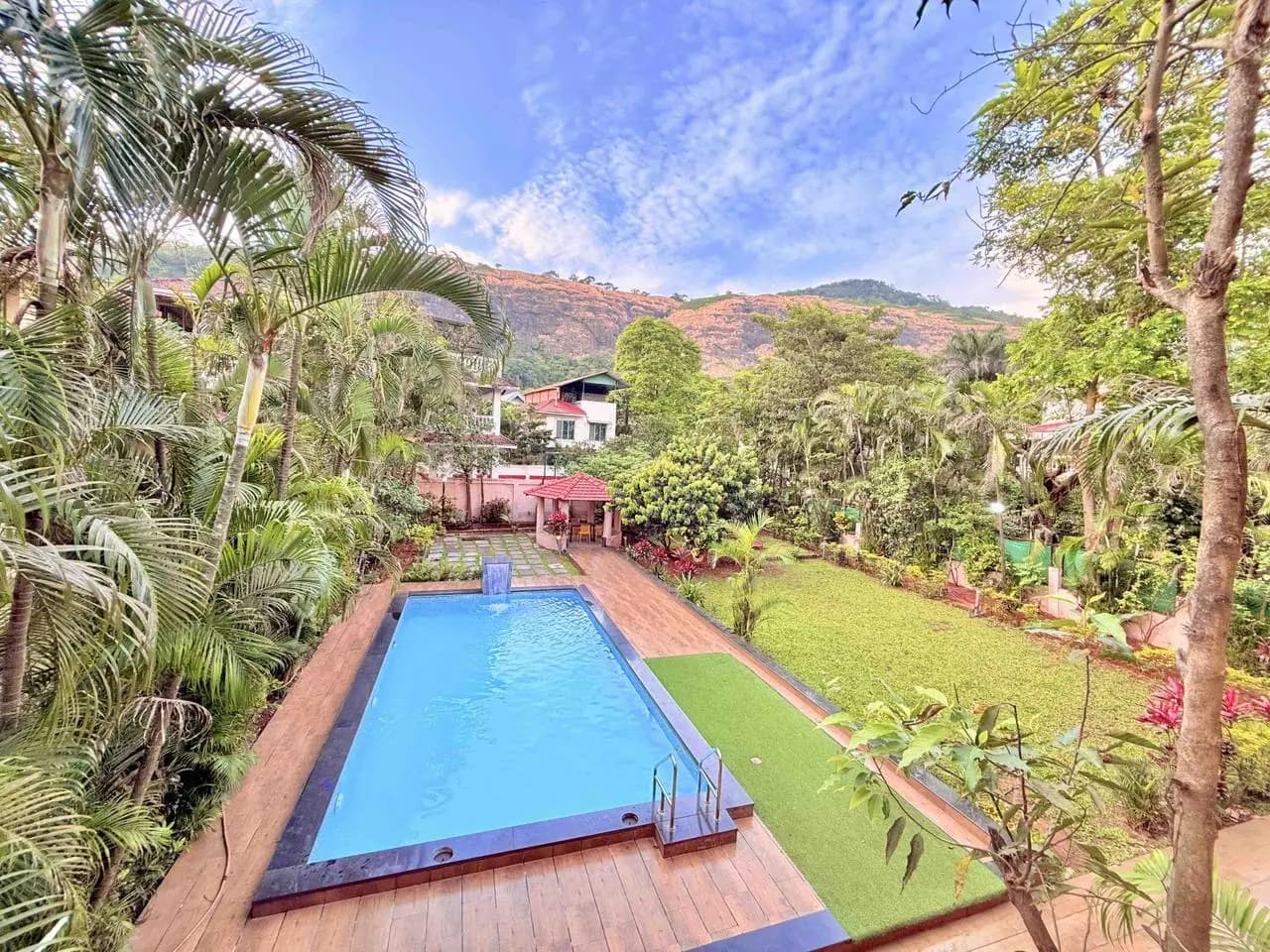 Private pool and garden with hills behind at a villa in Gold Valley, Lonavala
